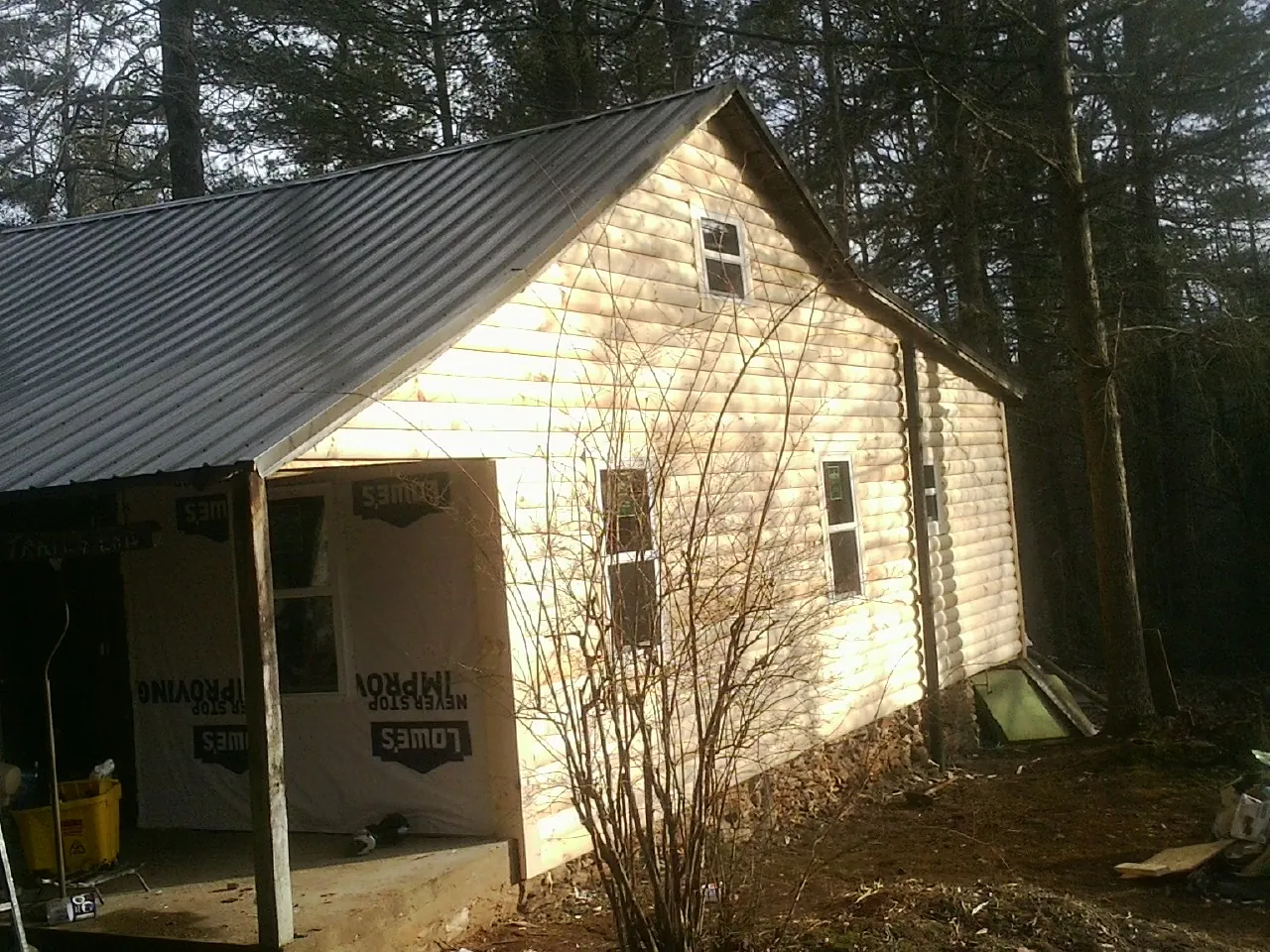 Log siding gable end under a dark metal roof edge in Mill Neck