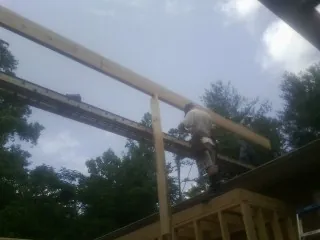 Carpenter setting a ridge beam over a new addition frame — Ice Dam Removal by Roofing Brothers in Mill Neck