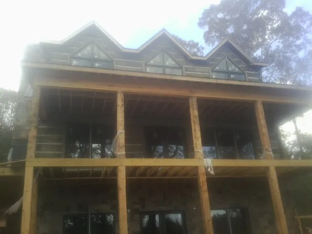 Dormers and porch framing on a large log home under construction — Roof Coating work by our crew in Mill Neck
