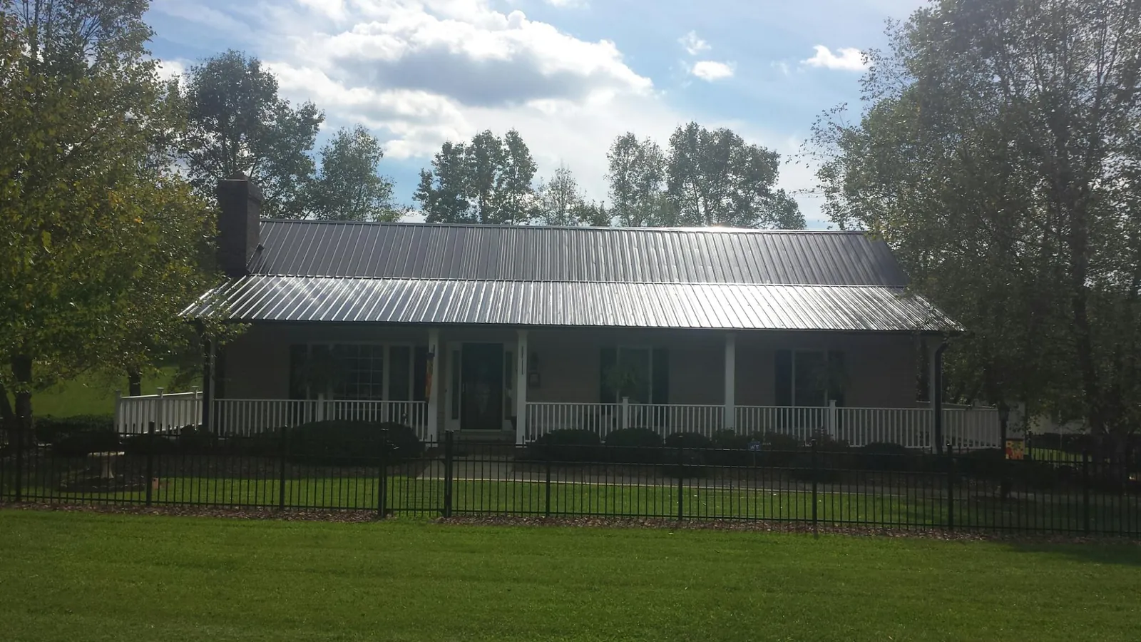 Gray metal roof on a brick ranch with a full width front porch — Gutter Guard Installation work by our crew in Mill Neck